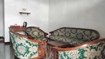 Una habitación con un conjunto de sofás, una mesa de centro de madera y una mesita con una tetera.