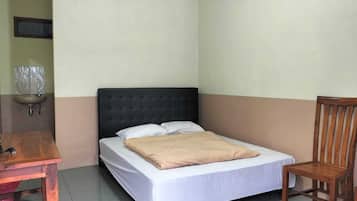A single bed with a headboard, a wooden chair, and a small table with a sink in a corner.