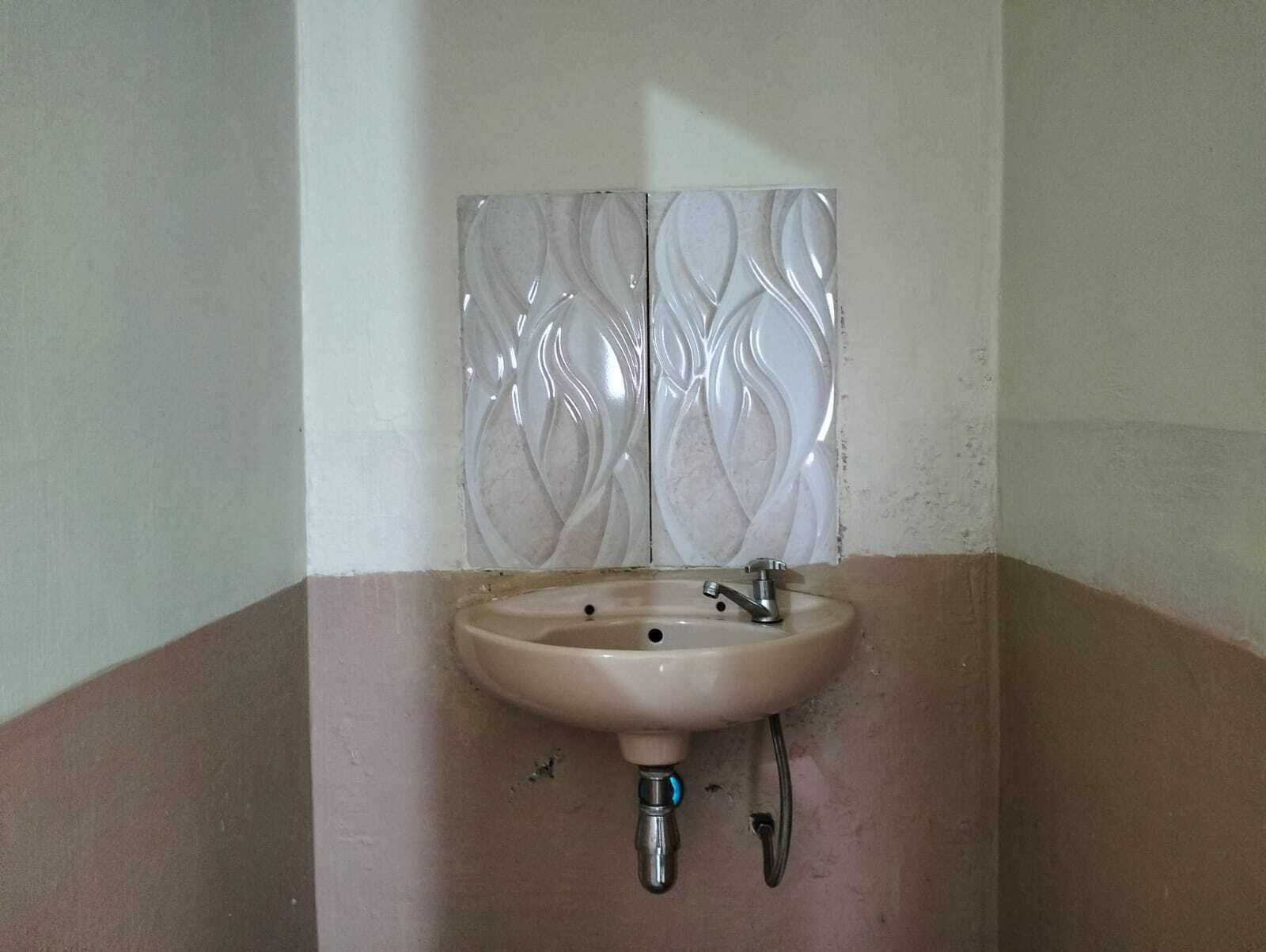Une salle de bain avec un lavabo, un miroir et un mur orné d’un motif décoratif.