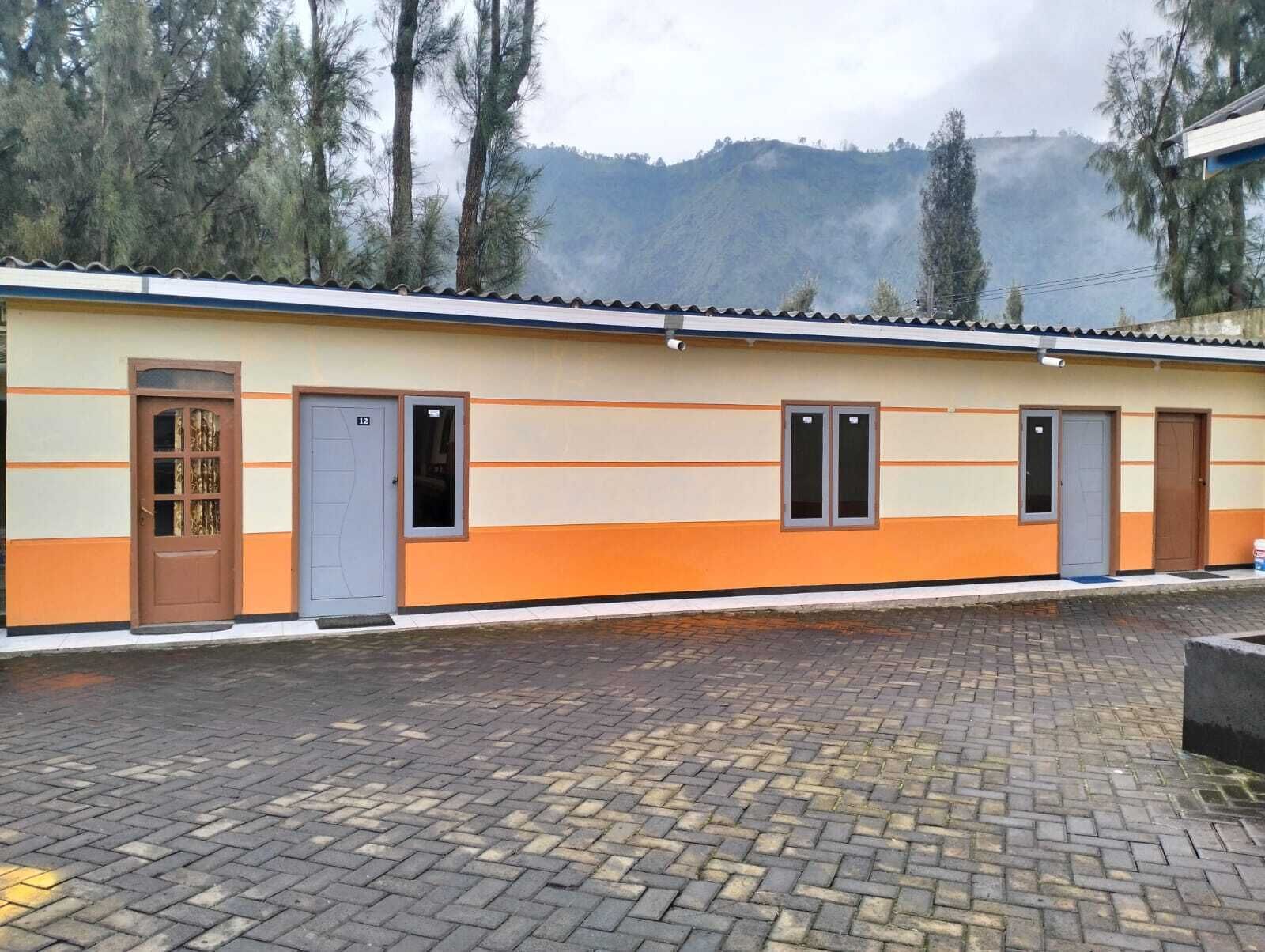 A building with a tiled roof, multiple doors, and a paved entrance area.