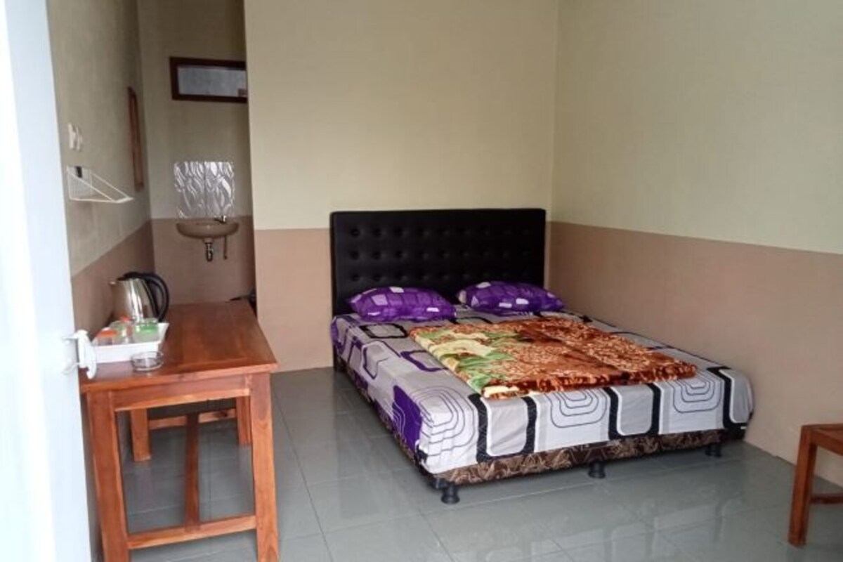A small, neatly arranged bedroom with a single bed, a bedside table, and a chair.