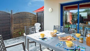 Un área de comedor al aire libre con una mesa lista para el desayuno, incluyendo pan, fruta y bebidas.