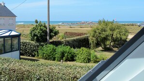 Vista costera con una casa, un jardín y el mar al fondo.