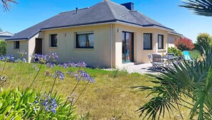 Une maison à deux étages, dotée d’un toit plat, de grandes fenêtres et d’un patio.