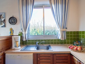 Enjoy cooking in this well-equipped kitchen with a large window, sink, coffee maker, and blender.