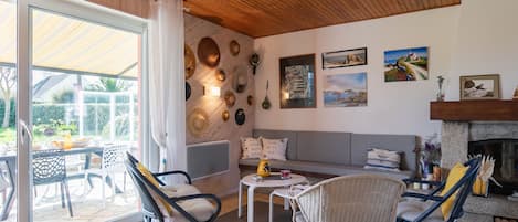 A spacious living area with a wooden ceiling, a large sliding glass door leading to a patio, and a fireplace.