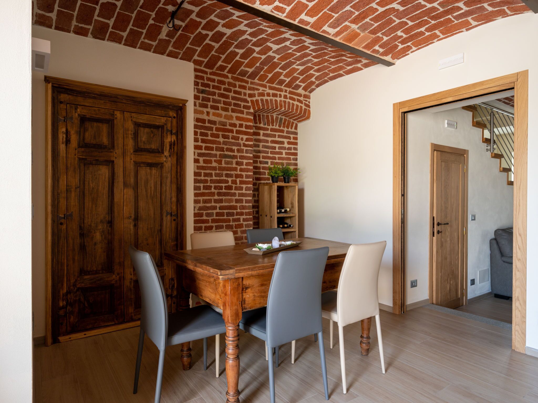 Un coin repas avec une table et des chaises en bois, un mur en briques et une porte en bois.
