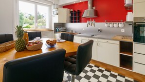 A modern kitchen with a red accent wall, a dining area with black chairs, and a checkered floor. - l'Atlantique by Interhome (Crozon-Morgat)