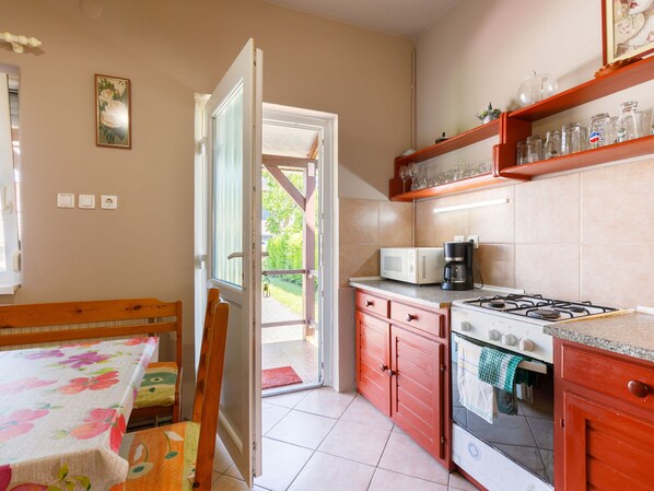 Una cocina con estufa, microondas y cafetera. Hay una mesa de comedor con sillas y una ventana que ofrece vistas al exterior.