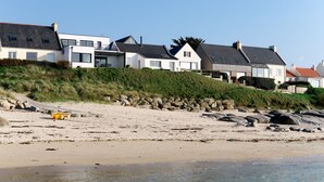 A beachfront property with modern houses, a sandy beach, and a rocky shoreline. - De la Digue by Interhome (Plouescat)