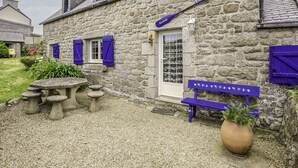 A stone building with a gravel patio, a small table, and a bench. - Kermalo by Interhome (Plouescat)