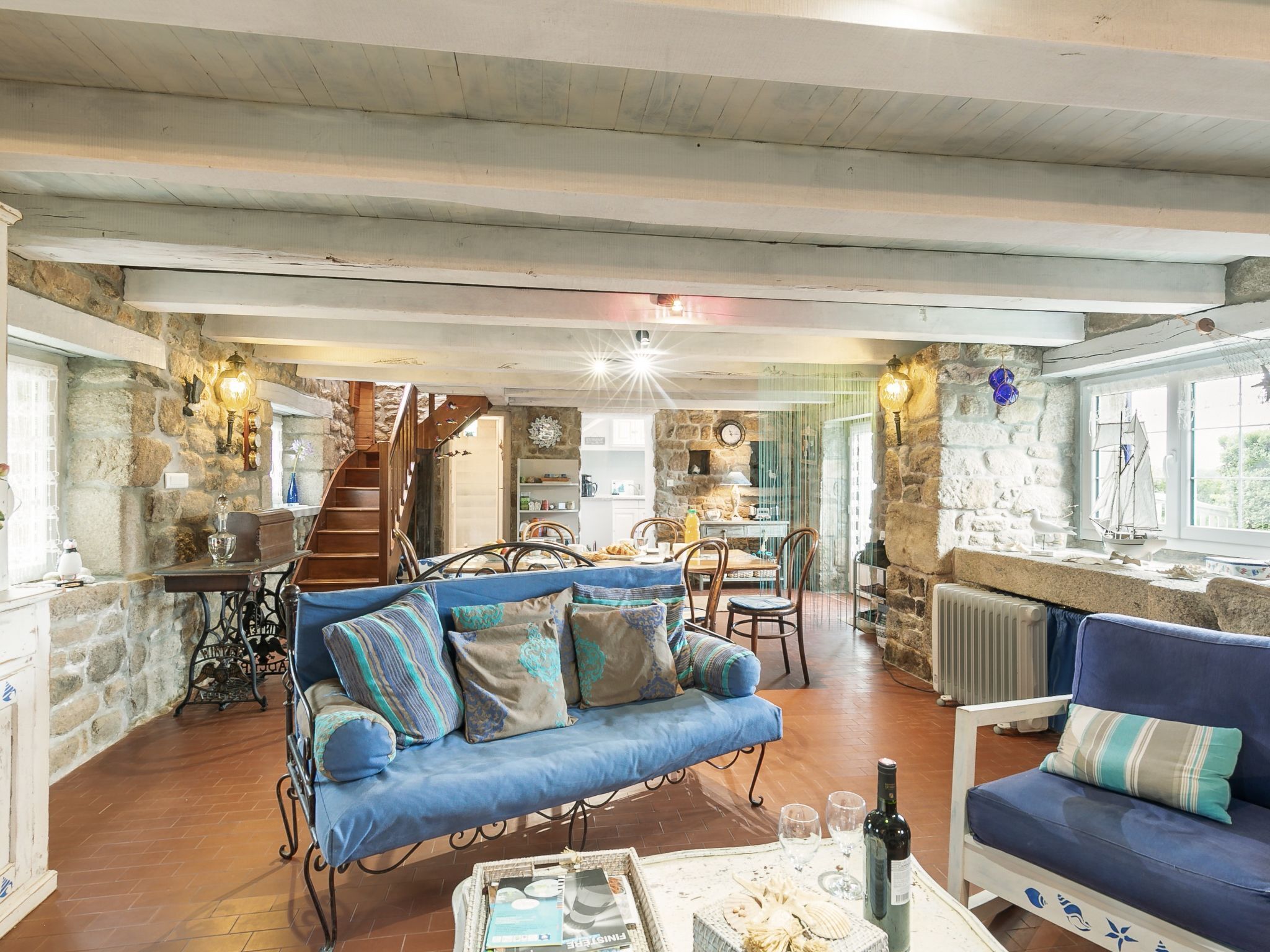 A cozy living room with a blue sofa, a wooden coffee table, and a stone wall.