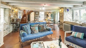 A cozy living room with a blue sofa, a wooden coffee table, and a stone wall. - Kermalo by Interhome (Plouescat)