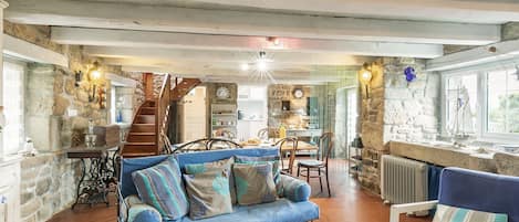 A cozy living room with a blue sofa, a wooden coffee table, and a stone wall.