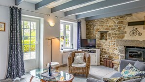 A cozy living room with a stone fireplace, a television, and a glass-top coffee table.