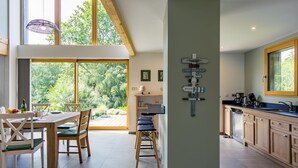 Una cocina amplia con un gran ventanal, armarios de madera y un comedor con mesa y sillas.