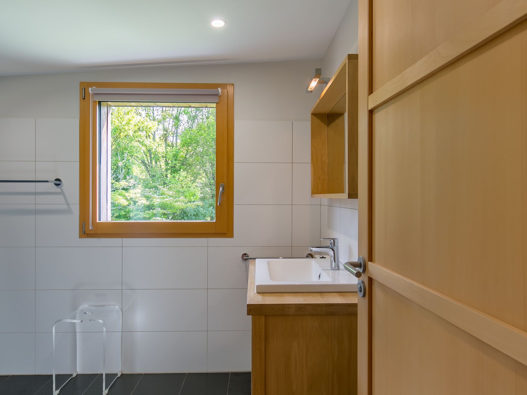 Ein modernes Badezimmer mit Fenster, Waschbecken und Holzschrank.