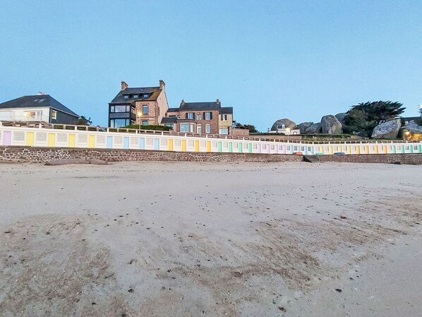 Ein Strand mit einem bunten Zaun und Häusern im Hintergrund.