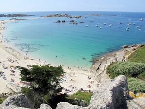 A beach with clear turquoise water, rocky outcrops, and boats. - Palacret by Interhome (Trégastel)
