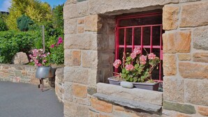 Un edificio de piedra con una ventana que tiene una celosía metálica roja.