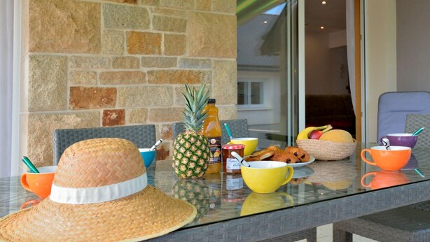 Una mesa de comedor con un sombrero de paja, una piña y diferentes alimentos para el desayuno.
