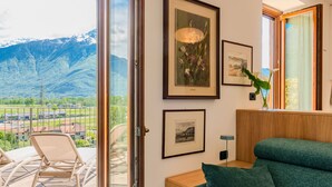 A room with a view of mountains, a sofa, a chair, and framed pictures on the wall. - Apartment Flat 1 by Interhome (Sorico Albonico)