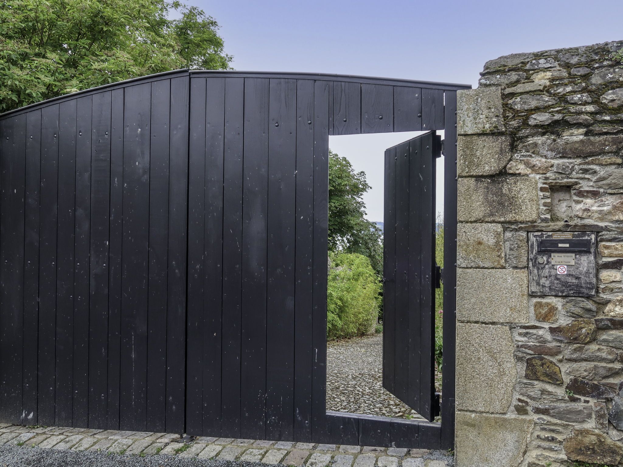 Una reja de metal negro, un muro de piedra y un marco de puerta de madera.