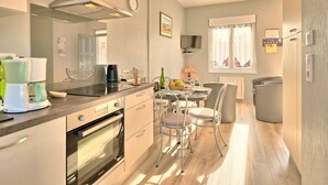 A modern kitchen with a built-in oven, a coffee machine, and a dining area with a table and chairs.