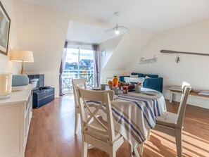A dining area with a table set for two, a sofa, and a view of the outside.