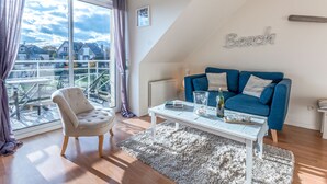 Een moderne woonkamer met een blauwe bank, een witte salontafel en een stadszicht door grote ramen.