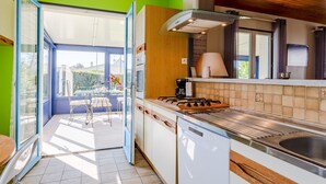 A modern kitchen with a glass door leading to a patio, a dishwasher, and a stove.