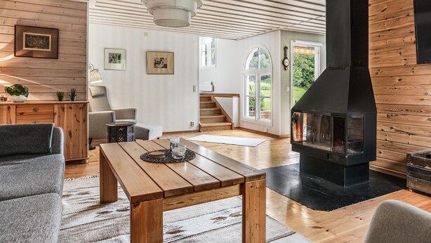 A spacious living room with a wooden ceiling, a fireplace, and a staircase leading to an upper level. - Kvarnfallet by Interhome (Ullared)