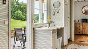 A kitchen with a large window, a clock, and a hanging light fixture. - Kvarnfallet by Interhome (Ullared)