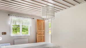 A bedroom with a large bed, a window with lace curtains, a wooden door, and a ceiling fan. - Kvarnfallet by Interhome (Ullared)
