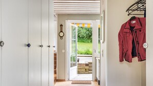 A hallway with a wooden floor, white doors, and a red jacket hanging on a rack. - Kvarnfallet by Interhome (Ullared)