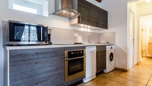 A modern kitchen with a built-in microwave, oven, dishwasher, and a coffee maker. - Le Clos Renard by Interhome (Commes)