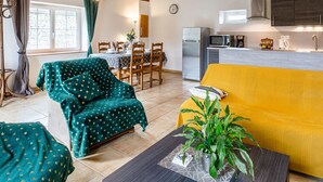 A cozy living room with a green armchair, a yellow sofa, and a dining area with wooden chairs and a table. - Le Clos Renard by Interhome (Commes)