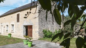 A stone building with a wooden door and windows, surrounded by greenery and a clear sky. - Le Clos Renard by Interhome (Commes)