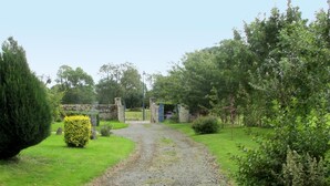 A gravel path leading to a stone gate in a lush garden. - Les Lutins by Interhome (Commes)
