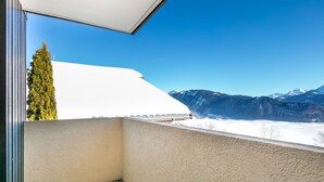 Ein Balkon mit Blick auf ein Gebirge und ein weißes Gebäude.