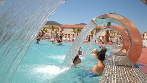A swimming pool with clear water, surrounded by palm trees and buildings with red-tiled roofs. - Demeures de la Massane 2P4 pers by Interhome (Argelès sur Mer)