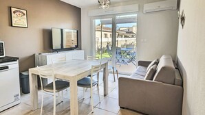 A modern apartment with a dining area, kitchenette, and a balcony with a view.