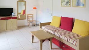 Ein Zimmer mit einer Couch, einem Holztisch, einem Stuhl, einem Fernseher und einem Schrank.