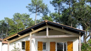 Ein eingeschossiges Haus mit geneigtem Dach, Holzbalken und einer Veranda mit Tisch und Stühlen.