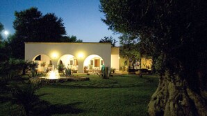 Un bâtiment moderne doté de trois fenêtres en arc de cercle et d’un jardin bien entretenu avec une fontaine.