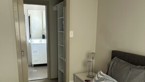 Une chambre à coucher avec un lit, une table de chevet, une lampe et une armoire.