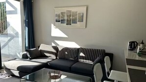 Un salon moderne avec une table basse en verre, un canapé rayé noir et blanc et un tableau encadré accroché au mur.
