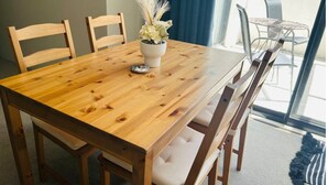 Une table de salle à manger en bois, accompagnée de quatre chaises, d’une plante en pot et d’un petit objet décoratif.