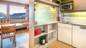 A compact kitchen with a microwave, stove, and a red box on the counter.