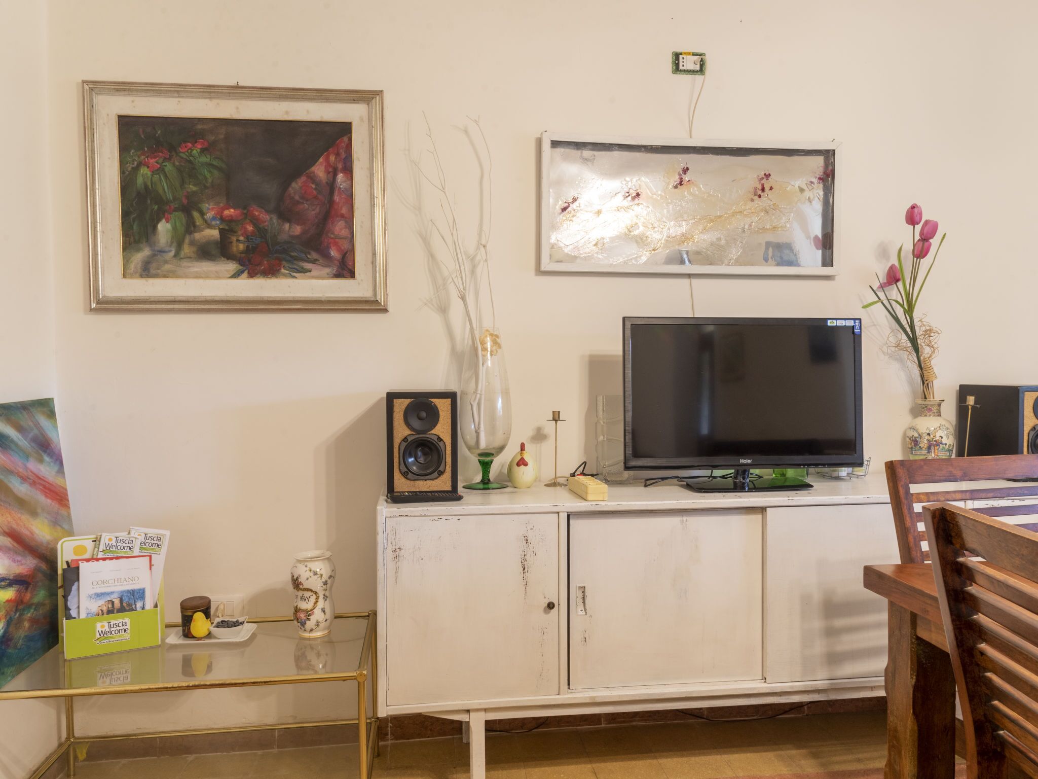 A living room with a television, a framed painting, and a decorative vase.